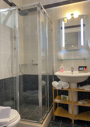 Un baño moderno con ducha envuelta en vidrio, un lavabo blanco y un espejo encima.