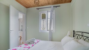 A bedroom with a bed, a window, a door, and a wooden ceiling. - Apartment '' with Shared Garden, Wi-Fi and Air Conditioning (Póros Kefalonias)