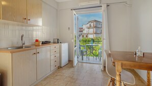 A kitchen with a sink, cabinets, and a dining area with a table and chairs. - Apartment '' with Shared Garden, Wi-Fi and Air Conditioning (Póros Kefalonias)