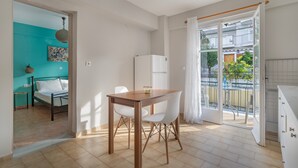 Een knus woongedeelte met een eethoek, een bed, een keuken en een balkon.