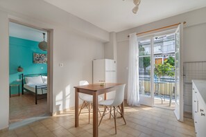 Un espace de vie compact comprenant un coin repas, un lit, une cuisine et un balcon.