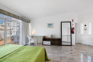 Habitación de hotel con cama, escritorio, silla, espejo y vistas al exterior.