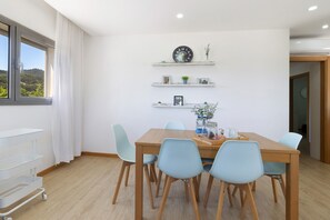 A dining area with a wooden table, light blue chairs, and shelves with decorative items.