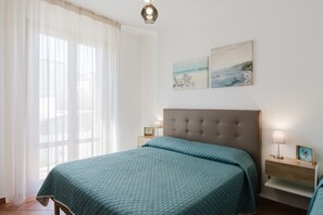 A bedroom with a large bed, a nightstand with a lamp, and two wall art pieces. - Apartment 'Kairos' with Shared Pool, Wi-Fi and Air Conditioning (San Vito Lo Capo)