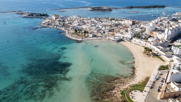 An aerial view of a coastal town with a beach, clear waters, and a fortified structure. - Holiday Home 'Solea Panoramic Sea View' with Sea View, Wi-Fi and Air Conditioning (porto cesareo)