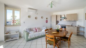 A compact living space with a dining area, kitchenette, and a sofa with decorative pillows. - Holiday Home 'Solea Panoramic Sea View' with Sea View, Wi-Fi and Air Conditioning (porto cesareo)