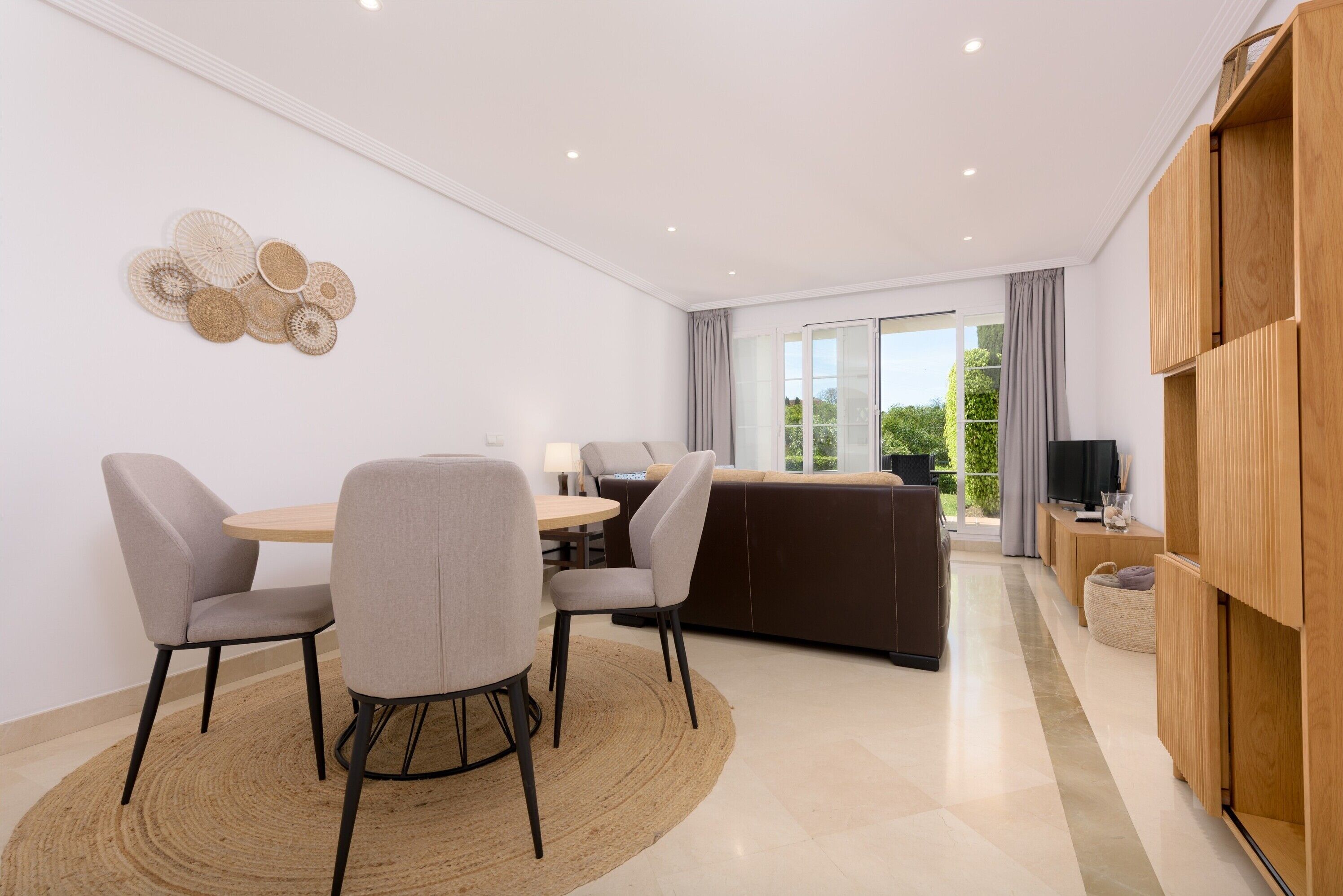 Un salon moderne comprenant un canapé, deux fauteuils, une table basse et un téléviseur.