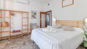 Een slaapkamer met een bed, een kledingkast, een stoel, een spiegel en een airconditioning.