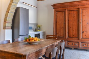 A kitchen with a wooden table, chairs, a refrigerator, and a wooden cabinet.