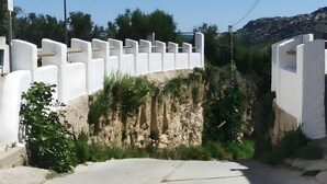 Un bâtiment blanc, avec un mur blanc et une route devant.