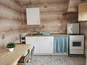 Uma cozinha compacta com pia, fogão e um espaço de refeições com mesa e cadeiras.
