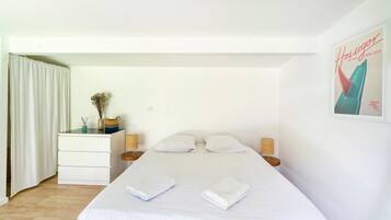 A bedroom with a bed, two bedside tables, a dresser, a window with curtains, and a poster on the wall.