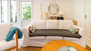 Un salon avec un canapé blanc, une table basse ronde en bois et un miroir au mur.