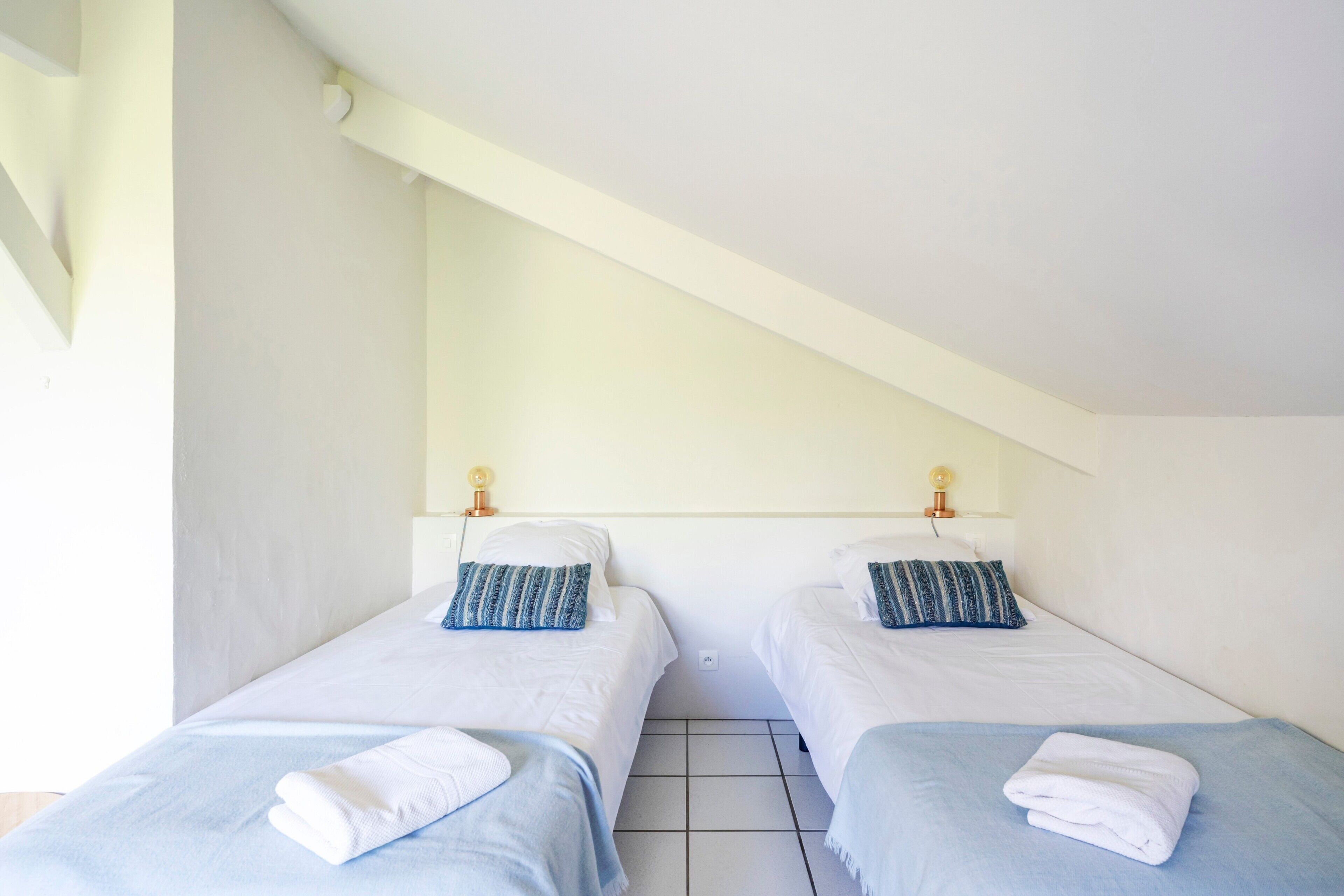 A room with two beds, each with a pillow and a folded towel.