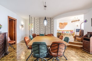 Ein Essbereich mit einem langen Holztisch, mehreren Stühlen und einer Wand mit Muster.