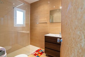 Een badkamer met een douche, toilet, wastafel en spiegel.