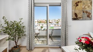 Un balcón con vistas a edificios, una planta en maceta, una mesa y una silla.