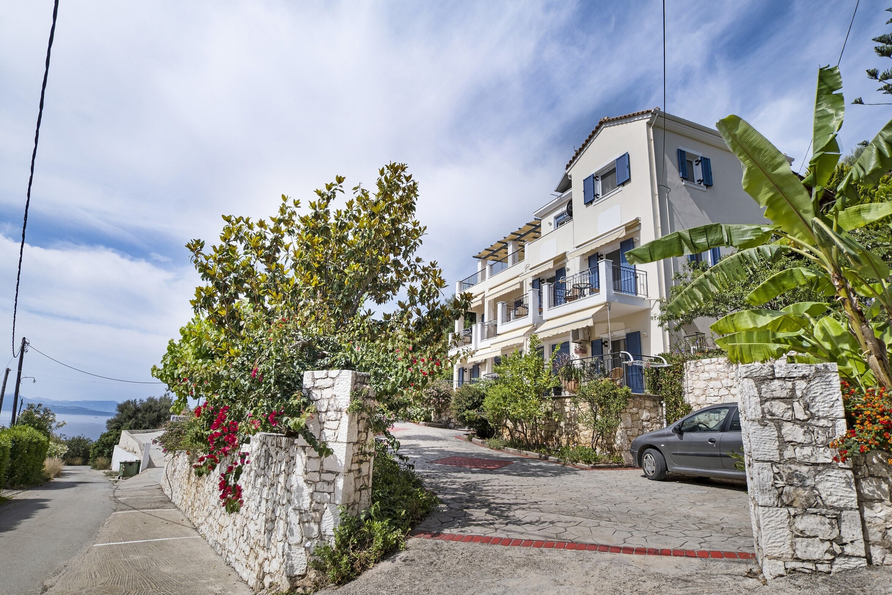 A residential building with a stone wall, a paved driveway, and a parked car.