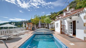 A swimming pool with a sunshade, lounge chairs, and a view of a hillside. - Vacation 'Pool House' with Mountain View, Wi-Fi and Air Conditioning (Vega de San Mateo)