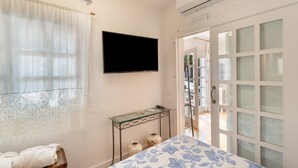 A bedroom with a bed, a TV, a glass table, and a door leading to a balcony. - Vacation 'Pool House' with Mountain View, Wi-Fi and Air Conditioning (Vega de San Mateo)