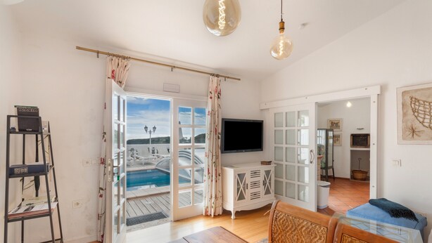 A living room with a wooden table, a TV, and a view of a pool. - Vacation 'Pool House' with Mountain View, Wi-Fi and Air Conditioning (Vega de San Mateo)