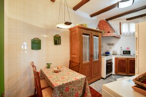 Une cuisine équipée d’une table à manger, de meubles de rangement en bois, d’un four à micro-ondes et d’un plan de travail recouvert de carreaux.