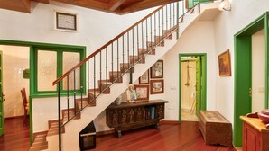 A staircase with wooden steps and a handrail, a green door, and a wooden cabinet with artwork. - Vacation 'Main House' with Mountain View, Wi-Fi and Air Conditioning (Vega de San Mateo)
