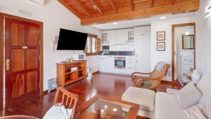 A living room with a sofa, wooden coffee table, TV, and a kitchen area with cabinets and a microwave. - Vacation 'Upper House' with Mountain View, Wi-Fi and Air Conditioning (Vega de San Mateo)