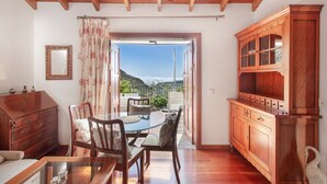 A room with a wooden ceiling, a dining table with chairs, a cabinet, and a view of a mountainous landscape through an open door. - Vacation 'Upper House' with Mountain View, Wi-Fi and Air Conditioning (Vega de San Mateo)