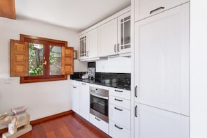 A kitchen with white cabinets, a black countertop, and a built-in oven.