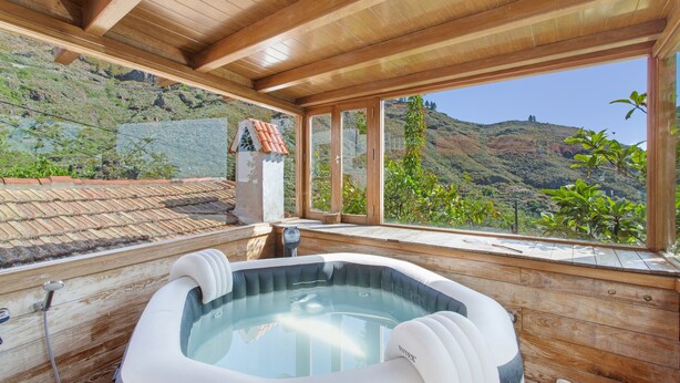 A wooden spa area with a hot tub, large windows, and a view of a mountainous landscape. - Vacation 'Upper House' with Mountain View, Wi-Fi and Air Conditioning (Vega de San Mateo)