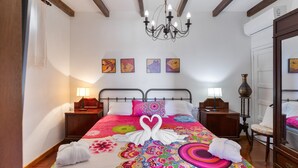 Een hotelkamer met een bed, een kroonluchter, kunst aan de muur en een spiegel.