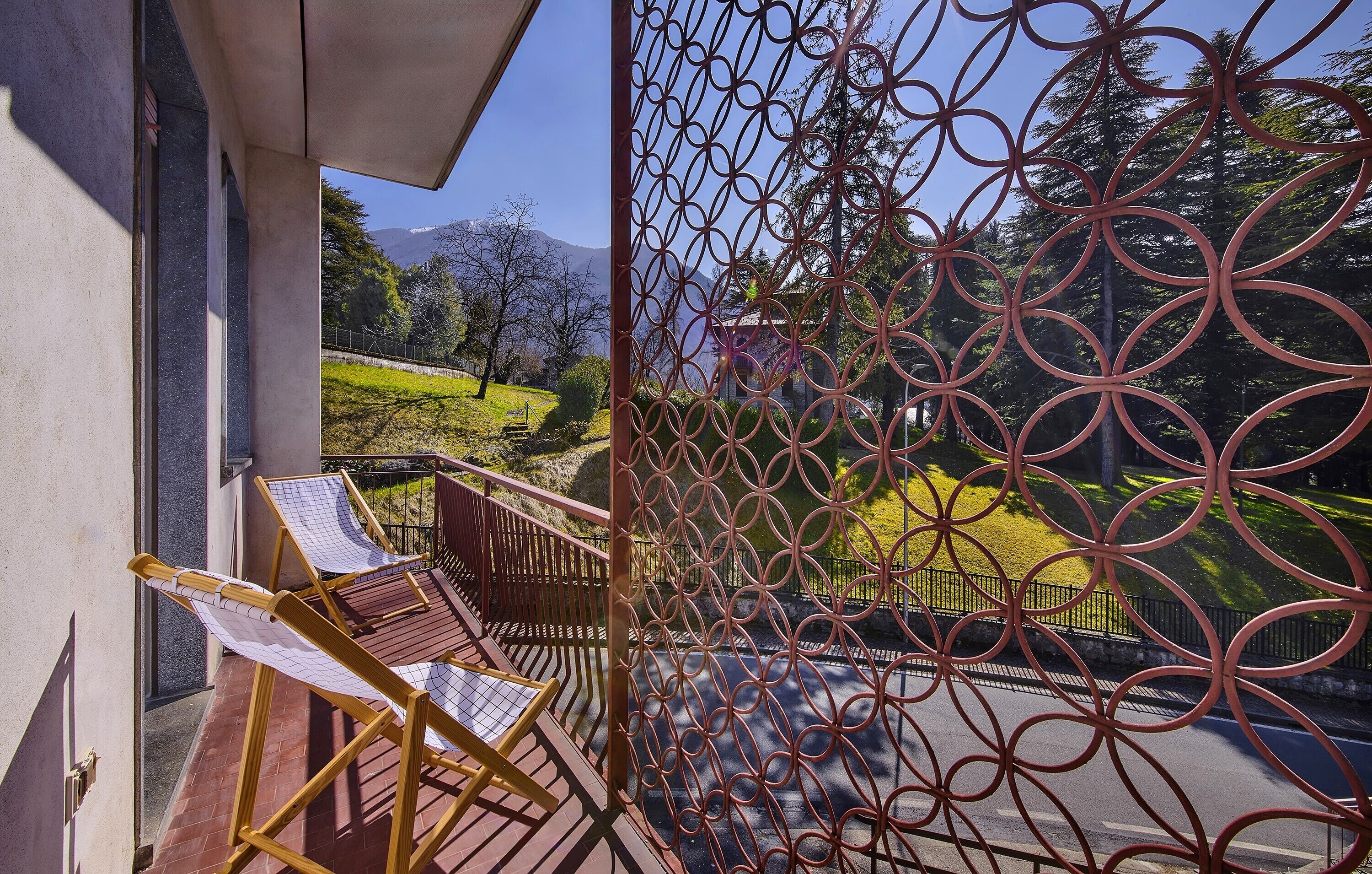 A balcony with a metal fence, a hammock, and a view of a mountainous landscape.