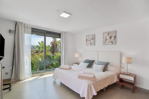 A bedroom with a bed, two bedside tables, a window with curtains, and artwork on the wall.