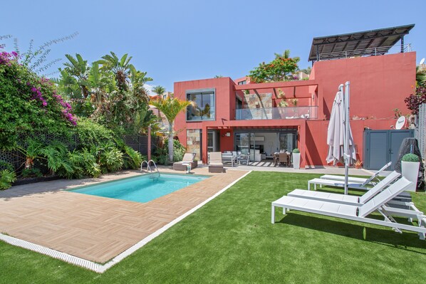 A modern house with a swimming pool, outdoor seating, and lush greenery. - Holiday Villa 'Alexandria's Retreat' with Sea Views, Wi-Fi and Air Conditioning (San Bartolome de Tirajana)