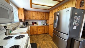 A kitchen with wooden cabinets, a stainless steel refrigerator, a stove, and a sink. - Circle Oak Lake View Family Home (Bradley)