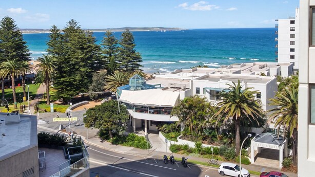 A coastal view with a road, buildings, and a beach. - Cronulla Ocean View, Steps to Beach (Cronulla)