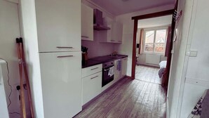 A compact kitchen with white cabinets, a black countertop, and a window providing natural light.
