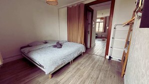 A bedroom with a bed, wooden flooring, and a wardrobe.