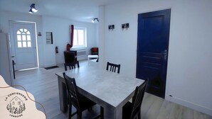 Un comedor con una mesa grande y sillas, una ventana con cortinas y una puerta azul.