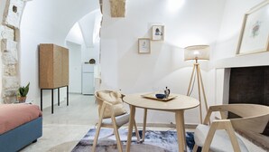 A modern living room with a round table, two chairs, a sofa, a floor lamp, and a fireplace.