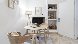 A cozy room with a round table, chairs, a fireplace, and shelves with decorative items.