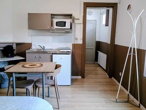A compact kitchen with a microwave, a small refrigerator, a sink, and a dining area with a table and chairs.