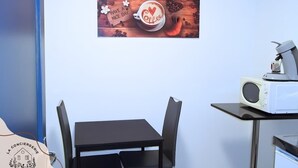 A room with a wooden coffee-themed wall art, a table with chairs, and a microwave on a counter. - Chez Serge N°102, wifi, parking gratuit, 2pers (Nœux-les-Mines)