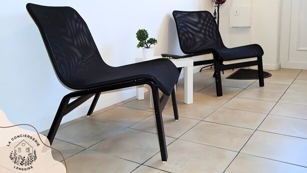 Two black chairs with a white table in a room with tiled flooring. - Chez Serge N°102, wifi, parking gratuit, 2pers (Nœux-les-Mines)