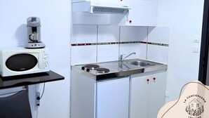 A compact kitchen with a microwave, coffee maker, and a small sink. - Chez Serge N°102, wifi, parking gratuit, 2pers (Nœux-les-Mines)