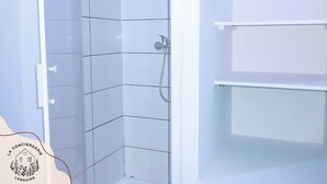 A bathroom with white tiled walls and a shower area. - Chez Serge N°102, wifi, parking gratuit, 2pers (Nœux-les-Mines)