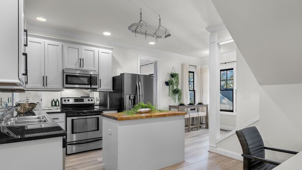 A modern kitchen with white cabinetry, stainless steel appliances, and a central island with a wooden countertop. - Luxury Modern Stay 3BR/2BA Pet Friendly Home Near UAB (Birmingham)