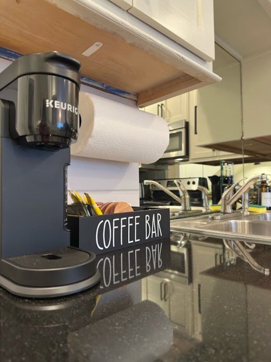 Une machine à café, un rouleau d’essuie-tout et une pancarte indiquant « Bar à café ».