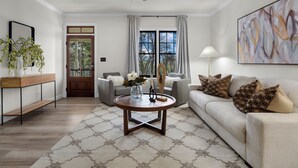 A modern living room with a round coffee table, a sofa, and a large abstract painting on the wall. - Luxury Modern Stay 3BR/2BA Pet Friendly Home Near UAB (Birmingham)